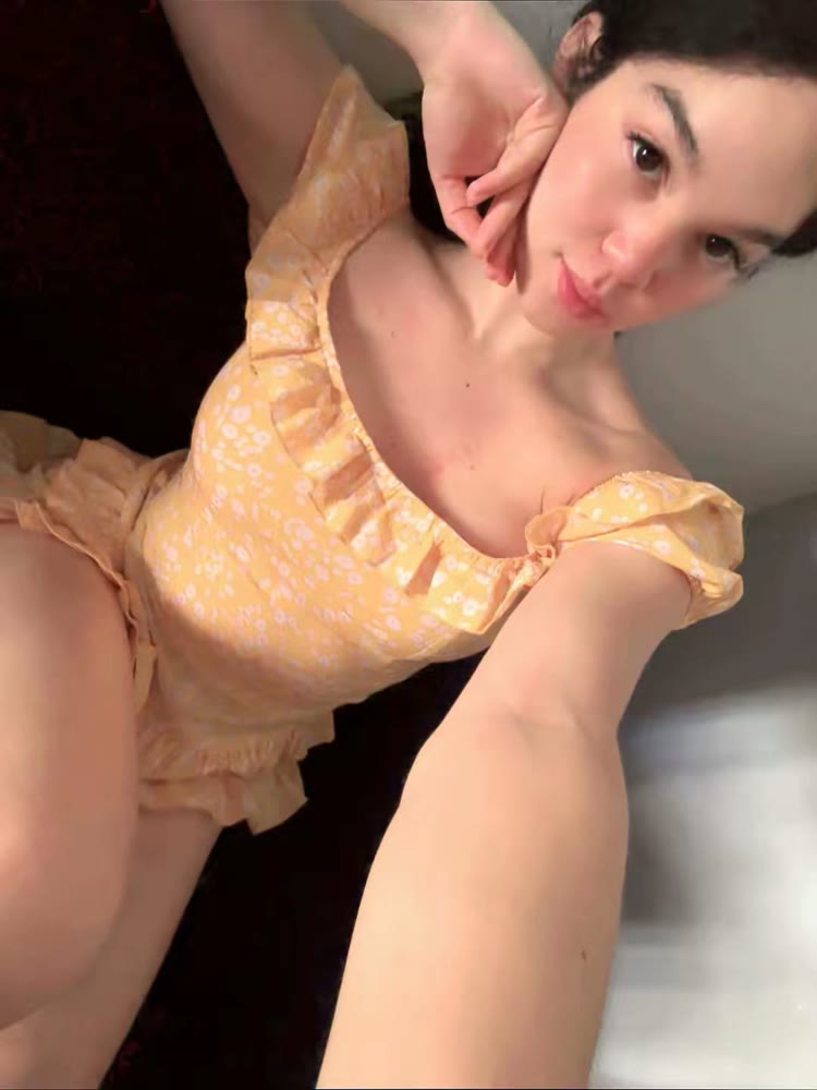 Woman in a yellow floral dress taking a playful selfie